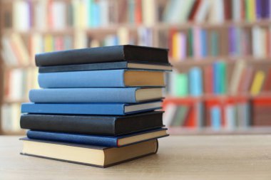 Ahşap masanın üzerindeki kitap yığını bulanık arka plana karşı