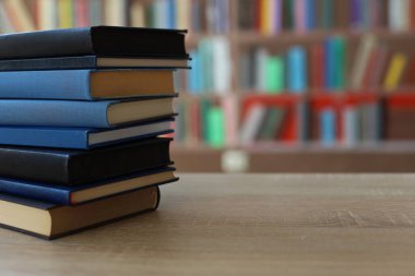 Bulanık arka plana karşı ahşap masadaki kitap yığını