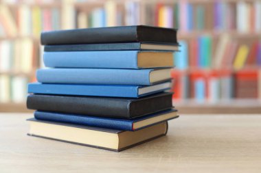 Kütüphanedeki ahşap masada yığınla kitap.