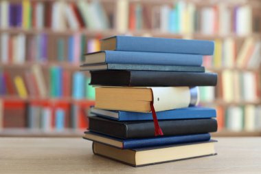 Kütüphanedeki ahşap masada yığınla kitap.