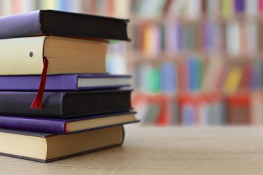 Kütüphanedeki ahşap masada yığınla farklı kitap.