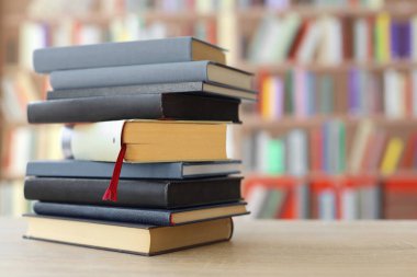 Kütüphanedeki ahşap masada yığınla kitap.