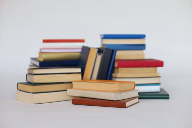 Masanın üzerinde beyaz arkaplan üzerine kitap yığını.