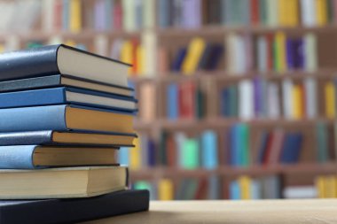 Kütüphanedeki ahşap masada yığınla kitap.