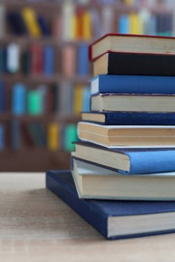 Kütüphanedeki ahşap masada yığınla kitap.