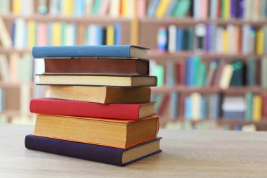 Tahta bir masanın üstünde duran bir yığın kitap.