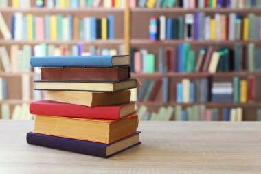 Kitaplığın önündeki masanın üzerinde bir yığın kitap.