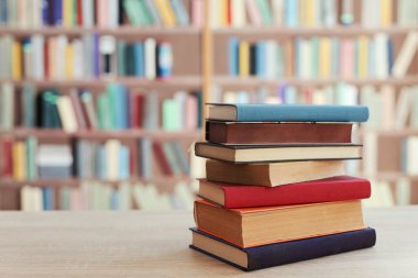 Kitaplığın önündeki masanın üzerinde bir yığın kitap.