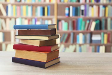 Kitaplığın önündeki masanın üzerinde bir yığın kitap.