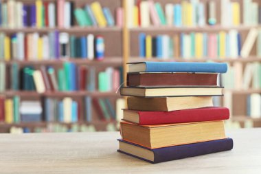 Kitaplığın önündeki masanın üzerinde bir yığın kitap.