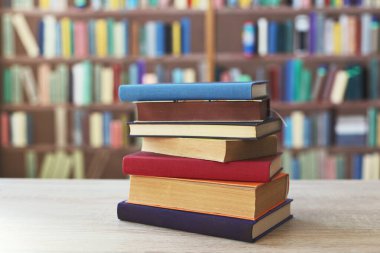 Kitaplığın önündeki masanın üzerinde bir yığın kitap.