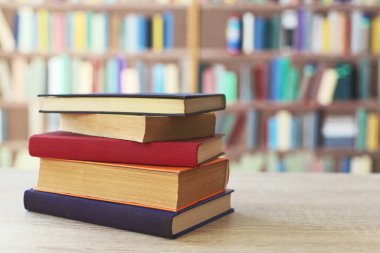 Tahta bir masanın üstünde duran bir yığın kitap.