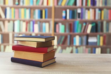 Kitaplığın önündeki masanın üzerinde bir yığın kitap.