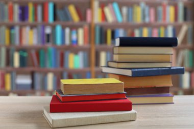 Kütüphanedeki ahşap masada yığınla kitap.