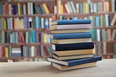 Kütüphanedeki ahşap masada yığınla kitap.