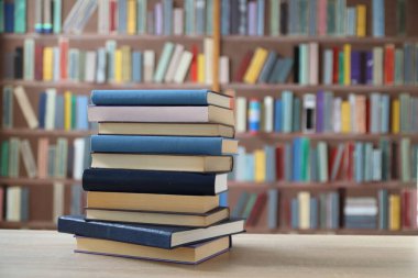 Kütüphanedeki ahşap masada yığınla kitap.