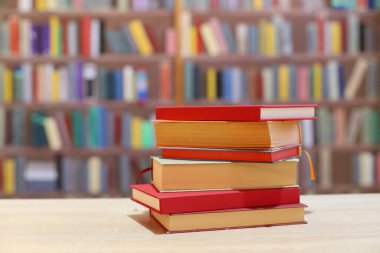 Kütüphanedeki ahşap masada yığınla kitap.