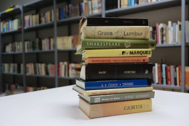 Kütüphanedeki ahşap masanın üzerindeki kitap yığını ünlü dünya yazarlarının en güzel ve en iyi kitapları.