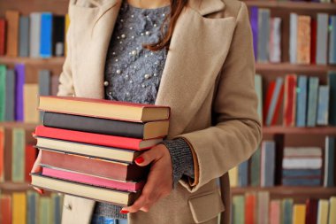 Kütüphanedeki ahşap masanın üzerindeki kitap yığını ünlü dünya yazarlarının en güzel ve en iyi kitapları.