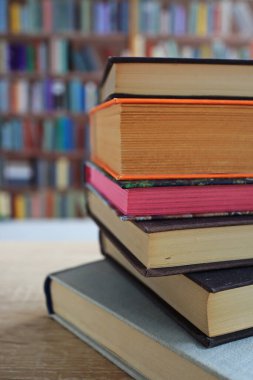 Kütüphanedeki ahşap masanın üzerindeki kitap yığını ünlü dünya yazarlarının en güzel ve en iyi kitapları.