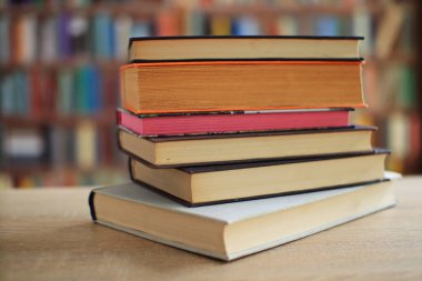 Kütüphanedeki ahşap masanın üzerindeki kitap yığını ünlü dünya yazarlarının en güzel ve en iyi kitapları.