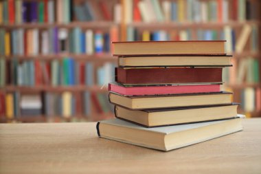 Kütüphanedeki ahşap masanın üzerindeki kitap yığını ünlü dünya yazarlarının en güzel ve en iyi kitapları.