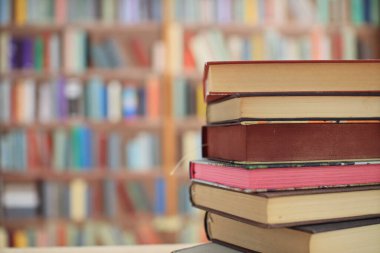 Kütüphanedeki ahşap masanın üzerindeki kitap yığını ünlü dünya yazarlarının en güzel ve en iyi kitapları.