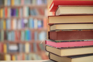 Kütüphanedeki ahşap masanın üzerindeki kitap yığını ünlü dünya yazarlarının en güzel ve en iyi kitapları.