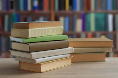 Kütüphanedeki ahşap masanın üzerindeki kitap yığını ünlü dünya yazarlarının en güzel ve en iyi kitapları.