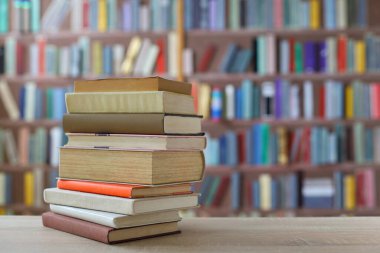 Ahşap bir rafın önünde yığınla kitap.