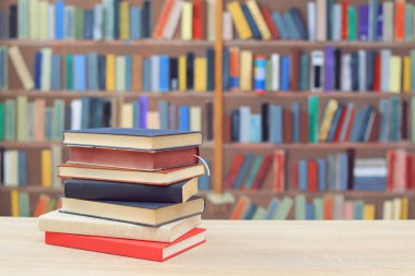 Kütüphanede masanın üstünde bir yığın kitap var..