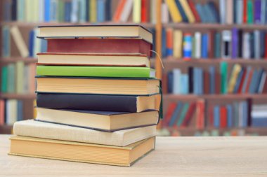 Kütüphanedeki ahşap masada yığınla kitap.