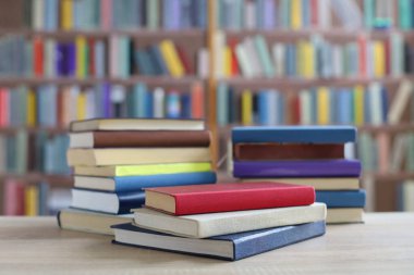Kütüphanedeki ahşap masanın üzerinde kitap yığını