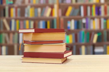 Ahşap masanın üzerinde bulanık arka plana karşı bir yığın kitap. Metin için boşluk