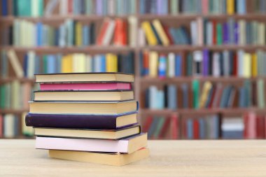Kütüphanedeki ahşap masada yığınla kitap.