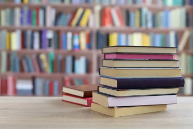 Kütüphanedeki ahşap masada yığınla kitap.