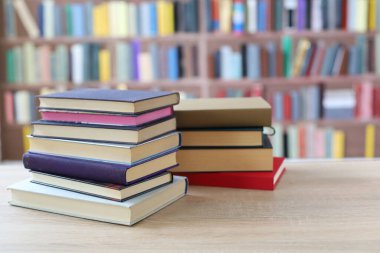 Kütüphanedeki ahşap masanın üzerinde kitap yığını