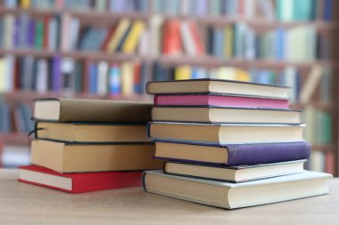 Kütüphanedeki ahşap masada yığınla kitap. Metin için boşluk