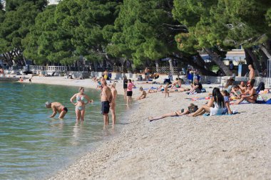 Makarska, Hırvatistan, 19.04.2024. Denizde yüzmek, kumsalda güneşli bir gün, 