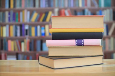 Kütüphanede, ahşap masanın üstünde bir yığın kitap. eğitim kavramı