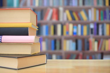 Kütüphanedeki ahşap masada yığınla kitap. eğitim