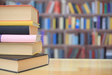 Kütüphanedeki ahşap masada yığınla kitap.