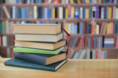 Kütüphanedeki ahşap masada yığınla kitap.