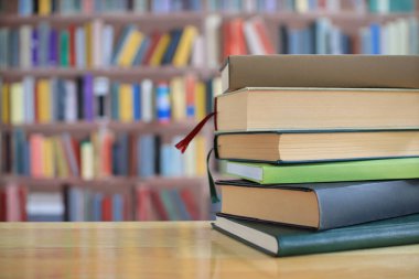 Tahta masadaki kütüphanede yığınla kitap.