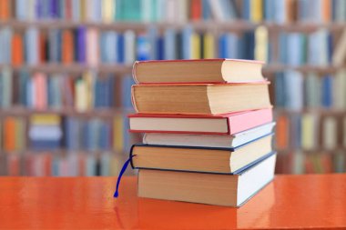Kütüphanedeki ahşap masada yığınla kitap.