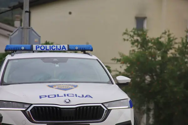 Beyaz çatılı bir polis arabası. Hırvatistan 'da polis arabası. Hırvat polisinin amblemi ve adı. Sokaktaki polis aracı..