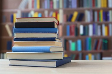 Kütüphanedeki ahşap masada yığınla kitap.