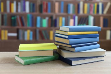 Kütüphanedeki ahşap masada yığınla kitap.