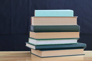 Yeşil arka plana karşı ahşap masa üzerindeki kitap yığını