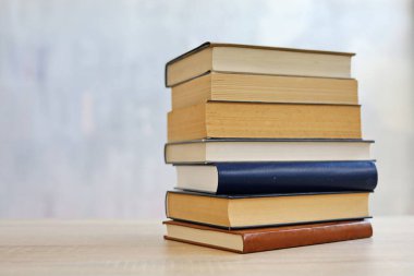 Ahşap arka planda bir yığın kitap, kütüphanenin arka planına karşı bir yığın kitap, kütüphanenin önünde bir yığın kitap, ahşap masa üzerine kitaplar.